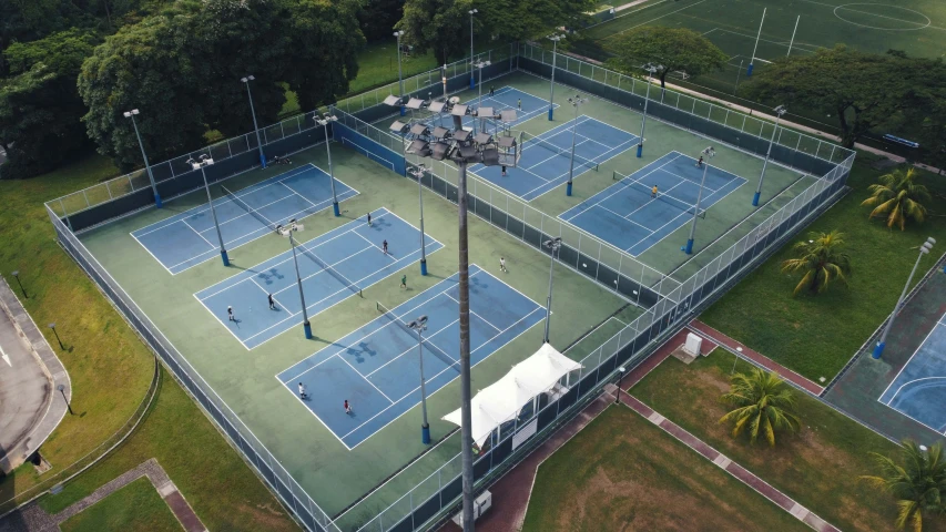 an aerial view of a tennis court surrounded by trees and grass