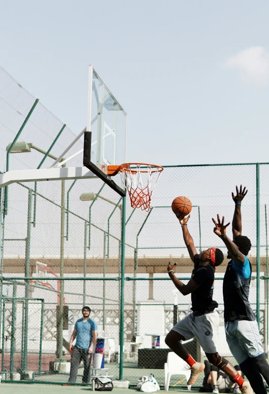 a man dunks a basketball as two others watch