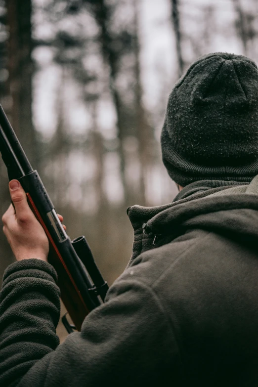 a man holding a rifle in the woods