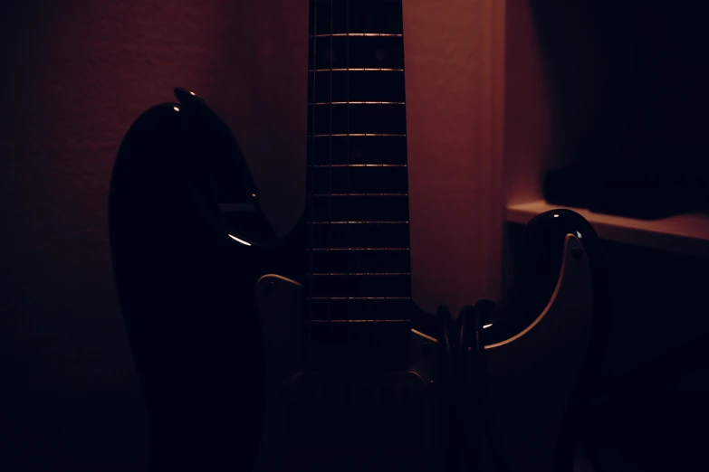 an acoustic guitar in the corner with its case sitting against a wall