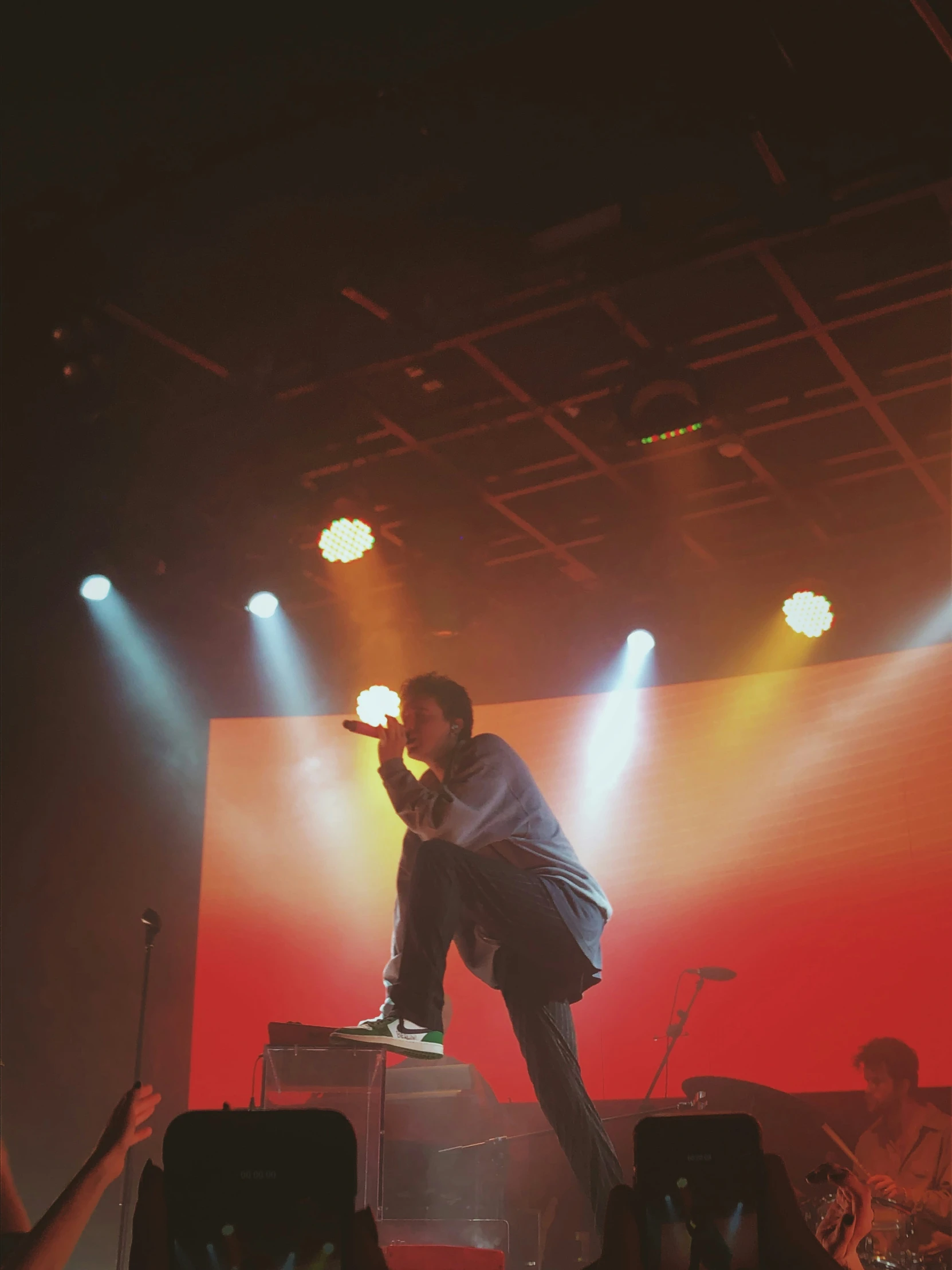 a man on stage with a microphone with lights on