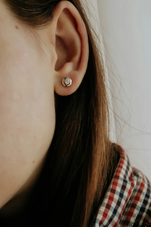 a close up of a person wearing ear studs