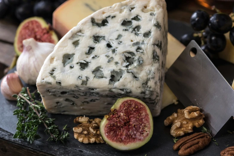 a cheese board has gs, figs, walnuts, nuts and cheese