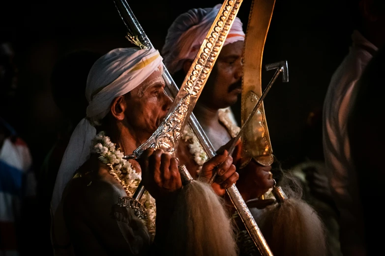 two men in elaborate indian garb holding onto ss pipes