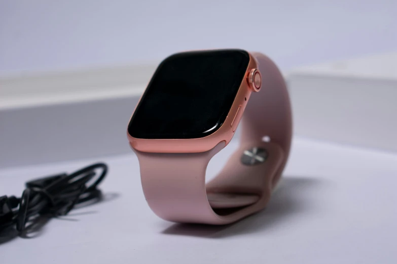 an iphone sits on top of a light pink band