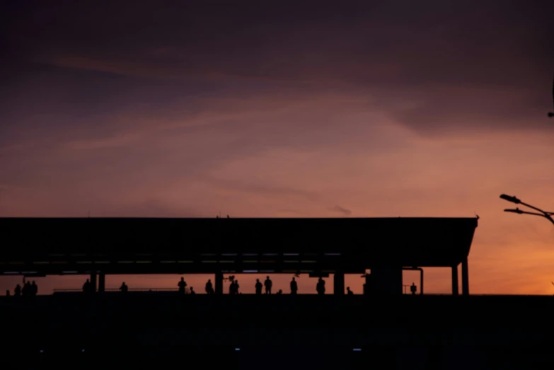 people are standing on a platform at dusk under the sun