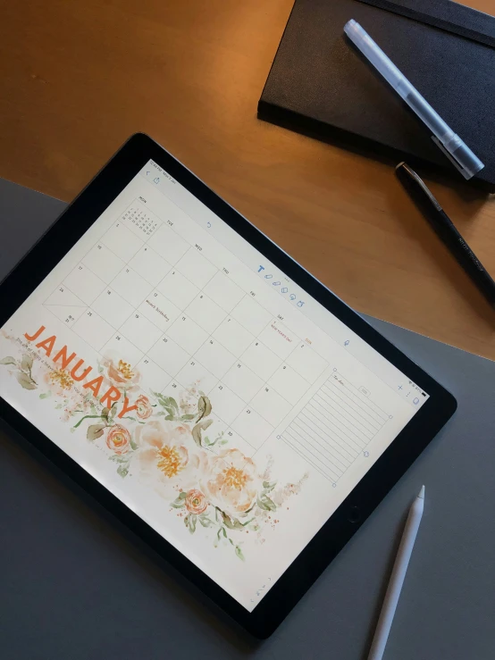 an ipad sitting next to a notepad and pen on a table