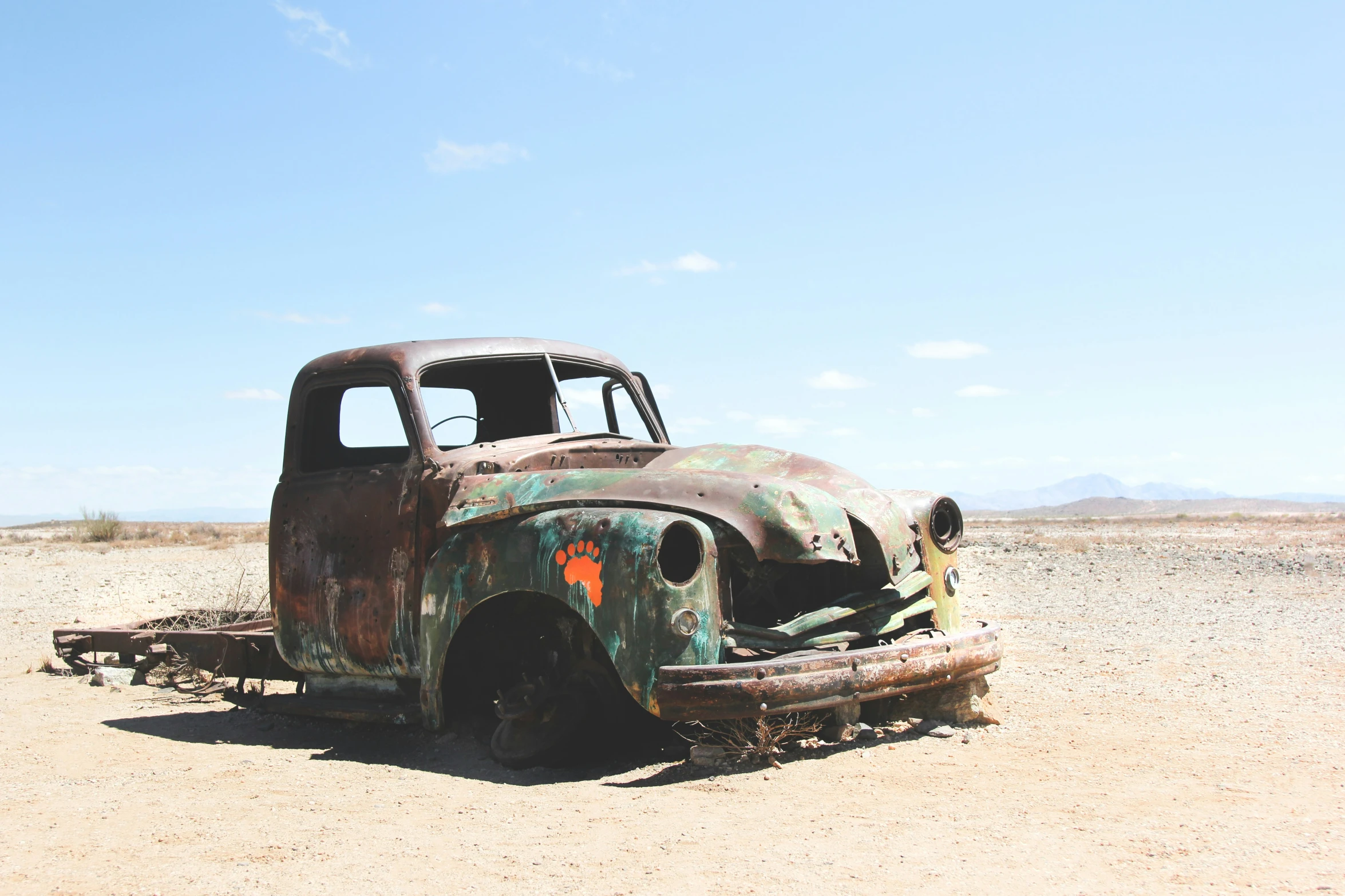 an old, rusty truck sitting in a desert field