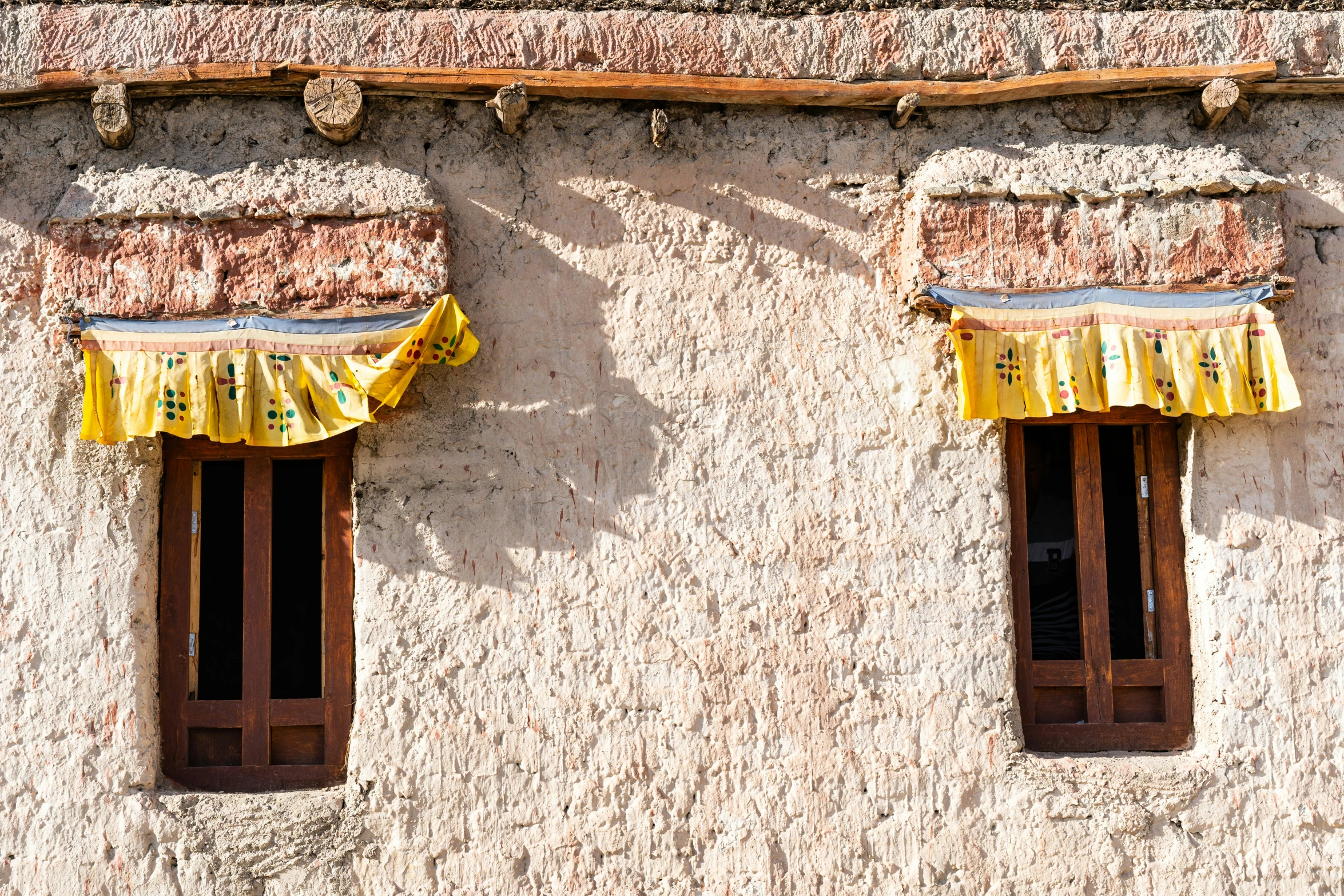 some yellow curtains are hanging off the sides of two windows