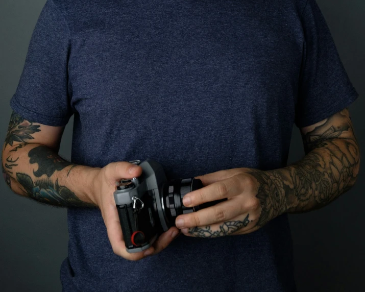 the man with tattoos is holding a camera