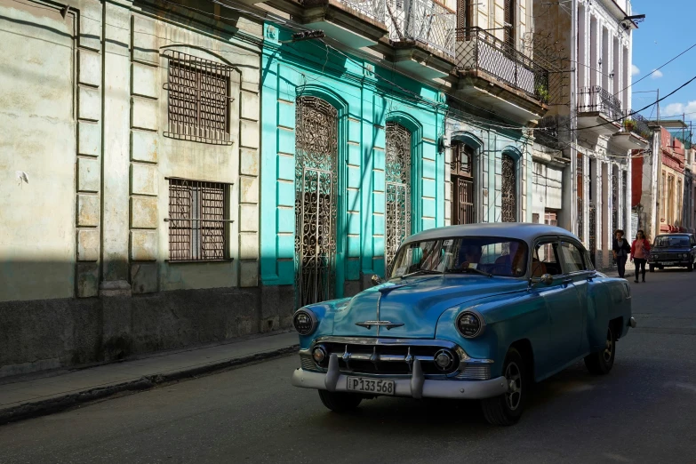 a blue old fashion car sitting in the street