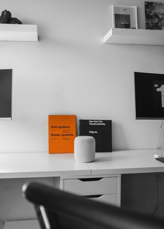 a desk that has a white vase and some black and white pos