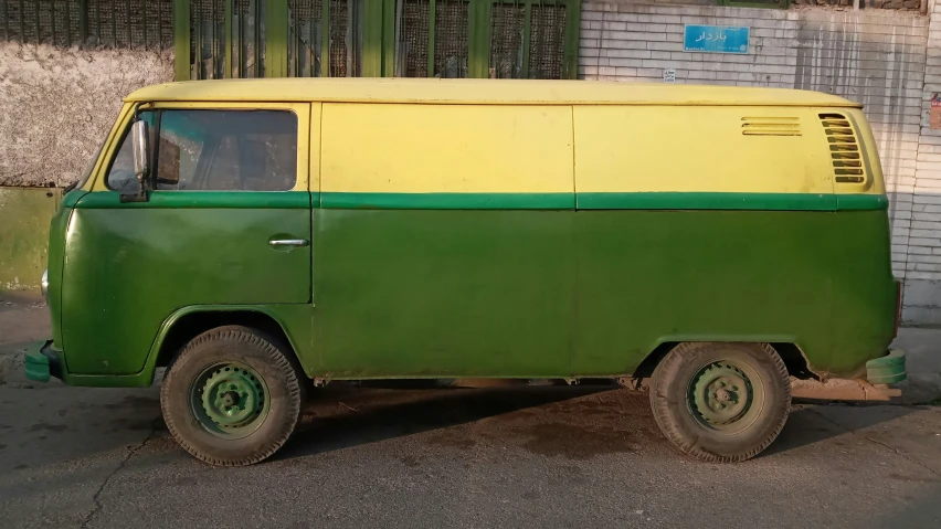 an old green and yellow van parked by a building