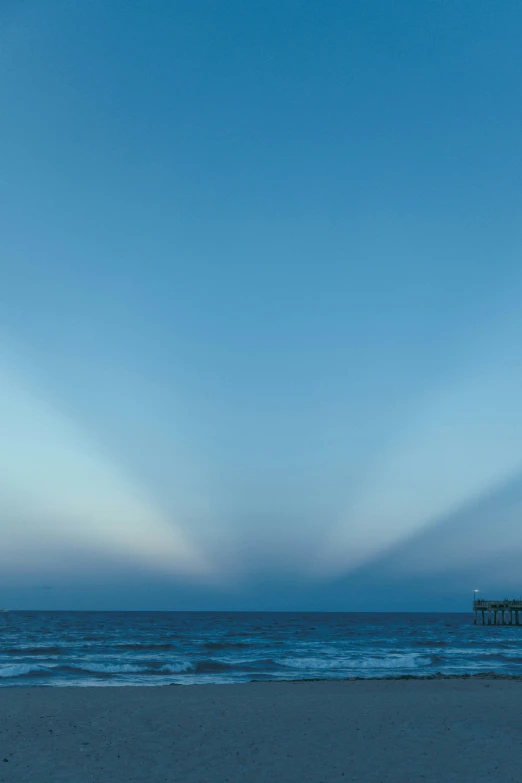 beach with pier with blue ocean and sky