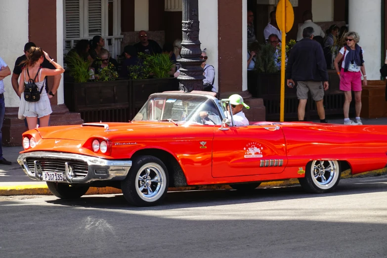 an orange convertible car driving down a road