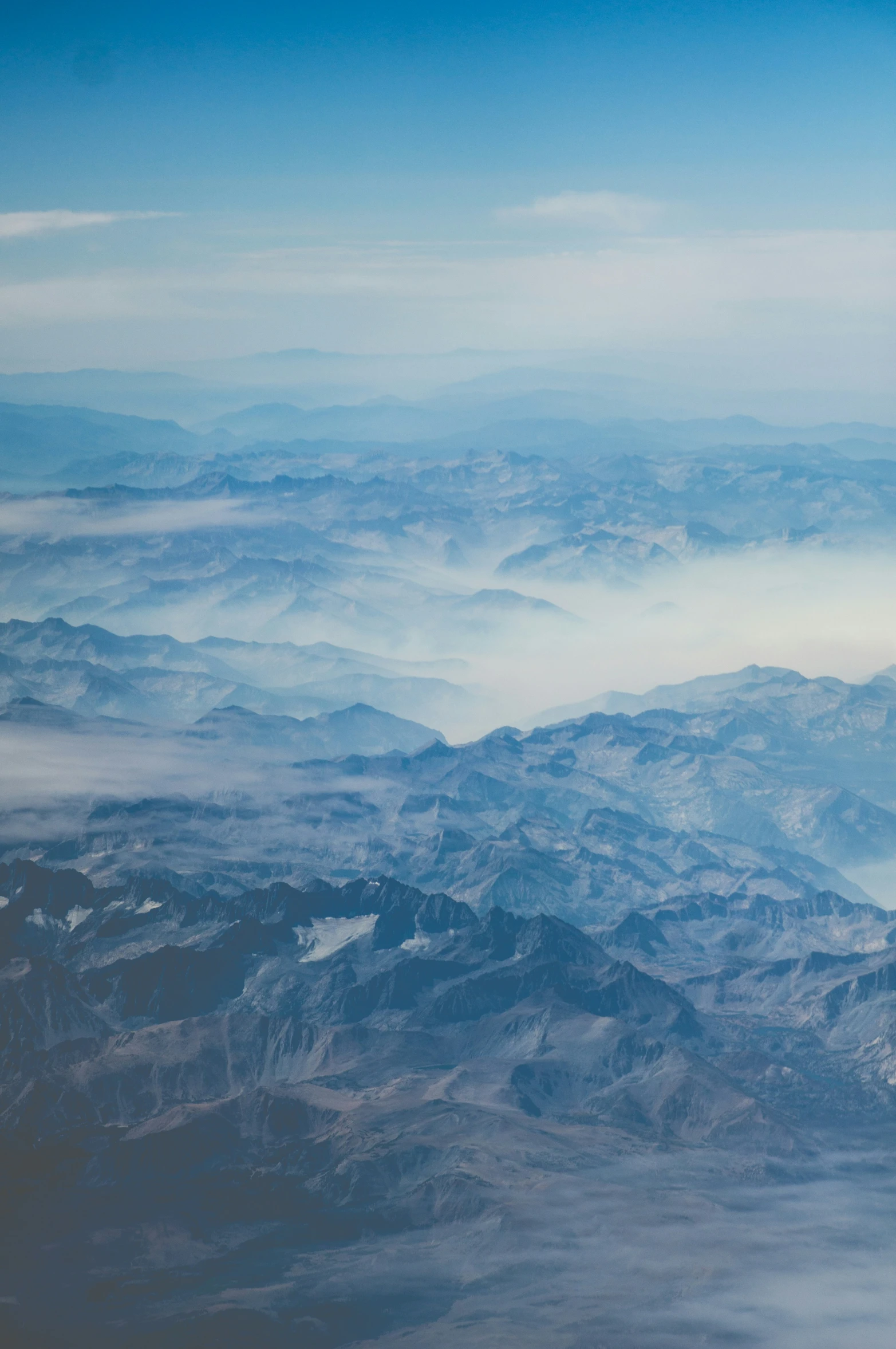 an airplane view down in the sky showing a distant mountain range