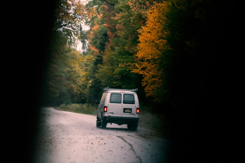 a car driving down a country road surrounded by trees