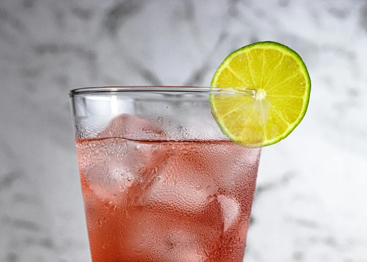 a close up view of a drink in a glass with lemon wedge