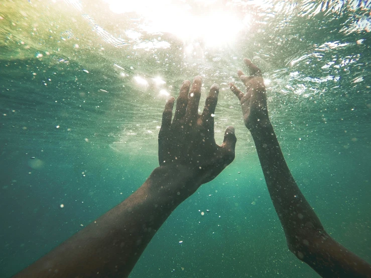 hands reach for the water surface under sunlight