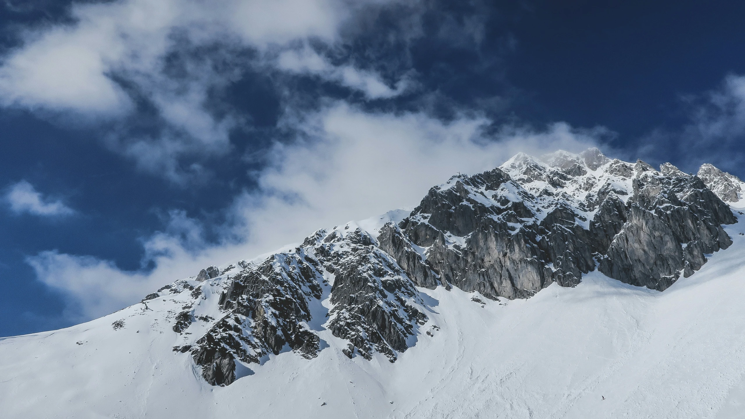 snow covered mountains with a few clouds in the sky