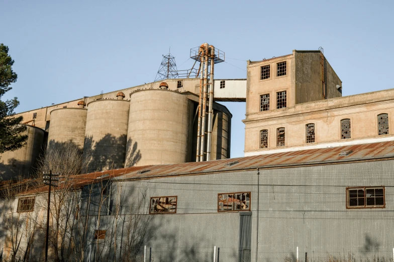 an abandoned building with silos and power lines