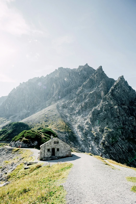 small stone building on a small gravel road near the mountains