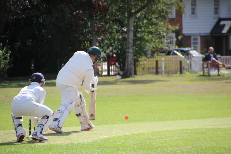 a man playing cricket while another watches on