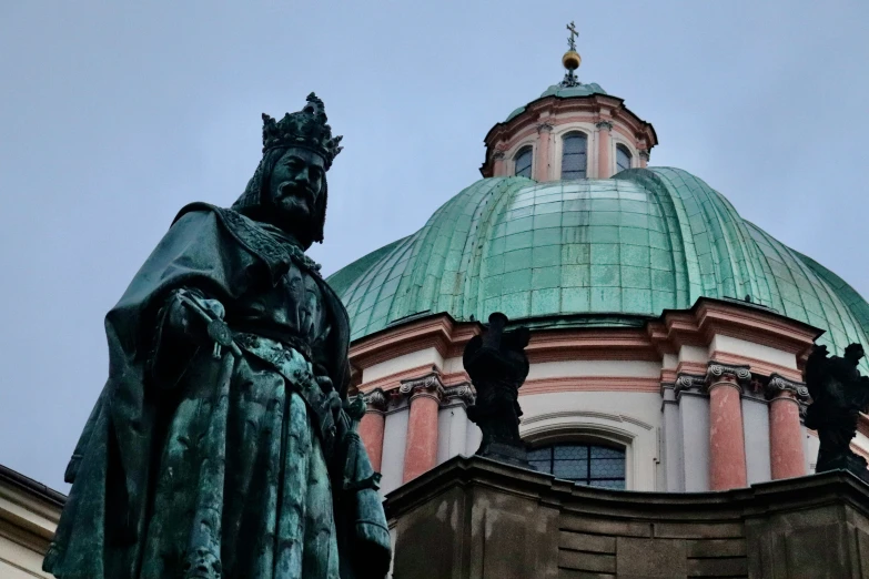 the statue is in front of a large green dome