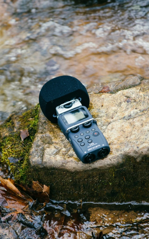 the cell phone is sitting on the rock by the water