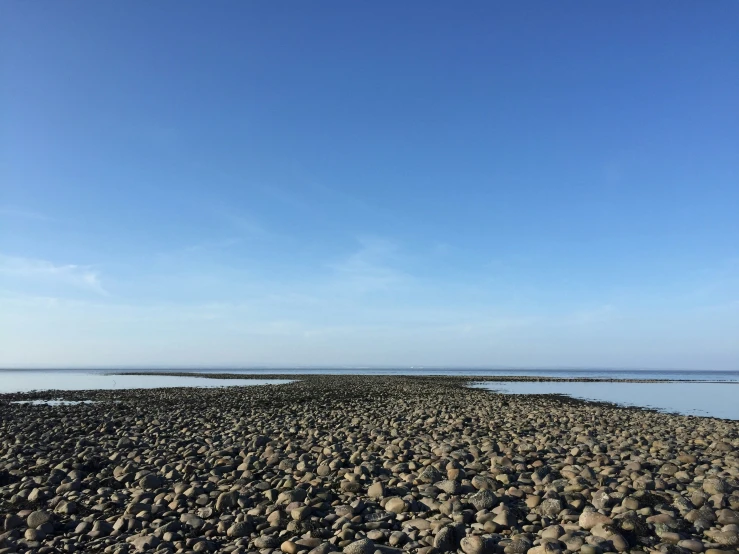 a view of the ocean with rocks on the shore and clear sky