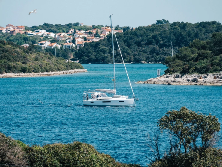 the white sailboat floats through blue water