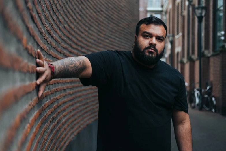 a man is leaning against a brick wall