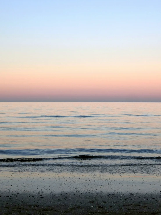 a woman walking on the beach carrying a surfboard