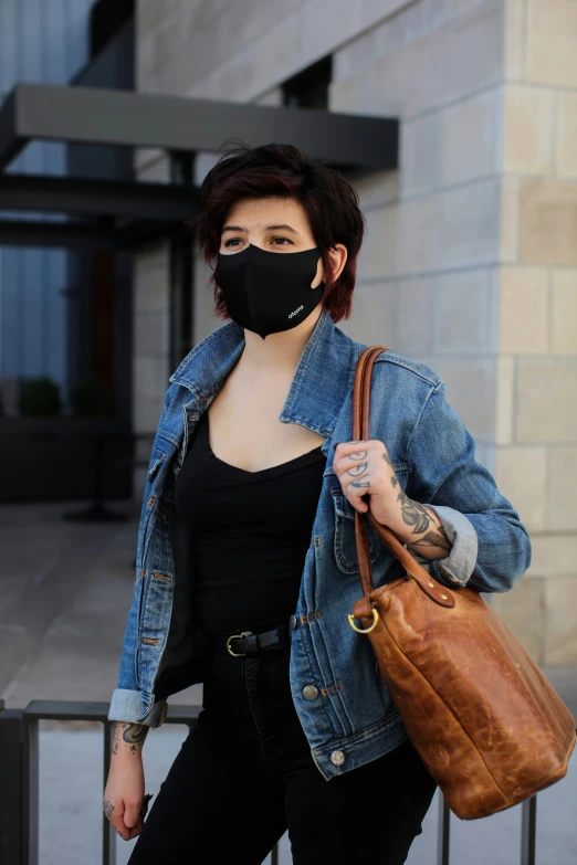 a woman carrying a brown bag and wearing a face mask