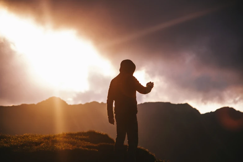 a man standing on top of a hill under a cloudy sky