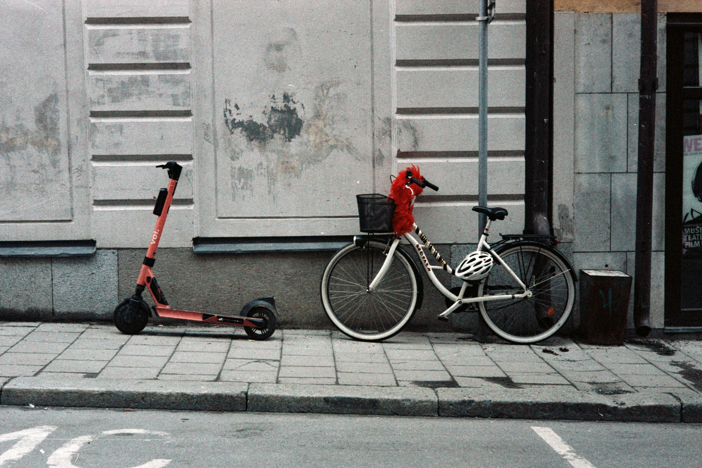 a scooter parked next to a bicycle on a sidewalk