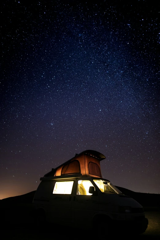 the night sky with stars and some bright lights are seen above a small white truck