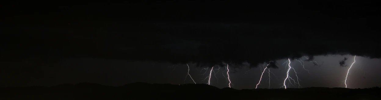 bright lights and smoke can be seen behind the clouds in the night sky