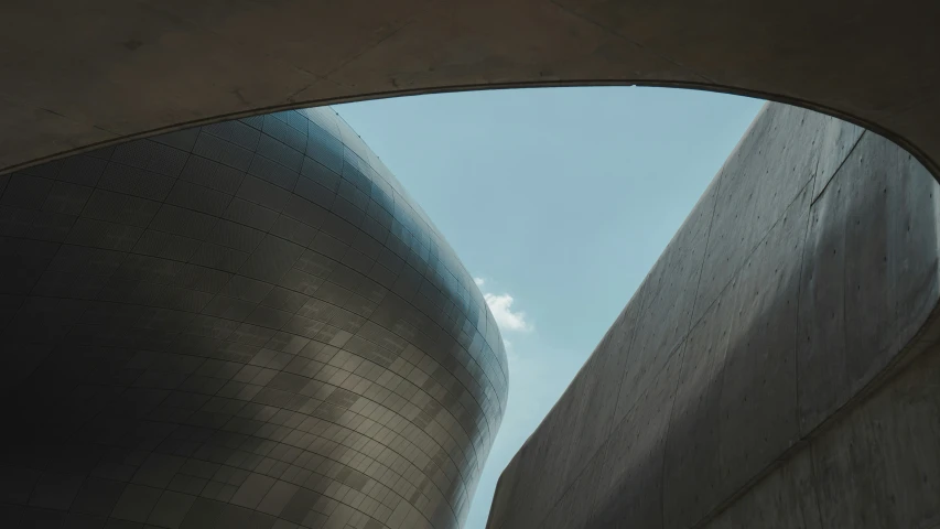 a curved concrete structure under a cloudy blue sky