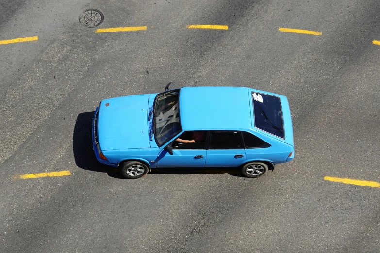 a blue vehicle driving down the middle of a street