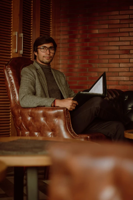 man sitting in leather chair holding a piece of paper