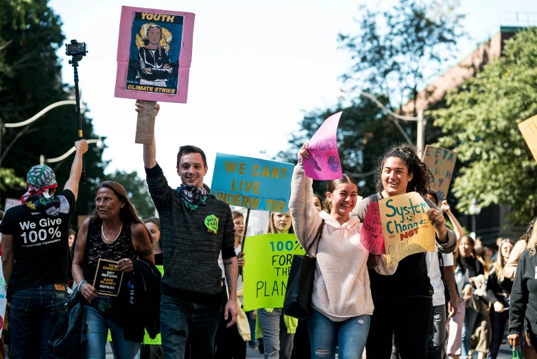 a group of people walking down the street holding up protest signs