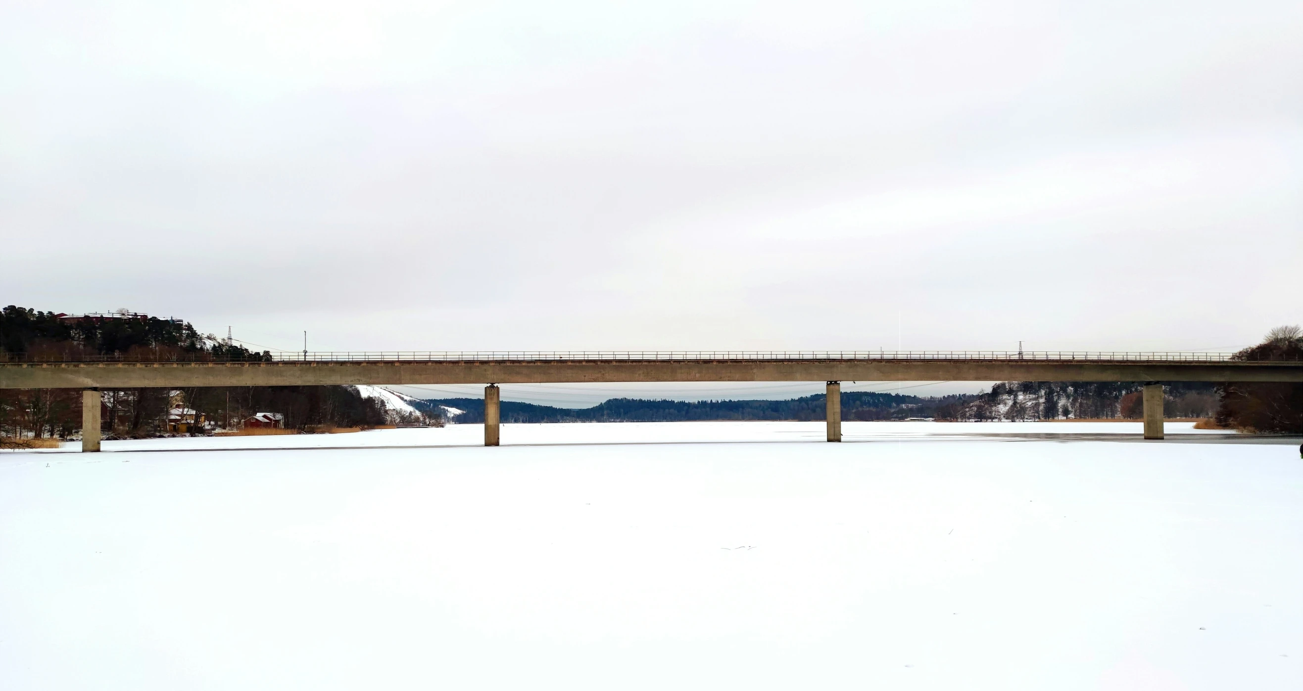 a snow covered landscape with the bridge that goes across a snowy field