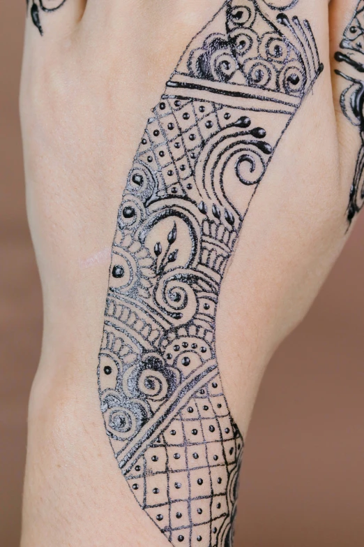 a woman's body with black paisley designs on her hands