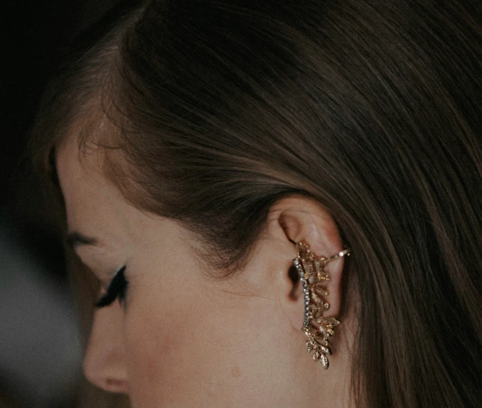 a woman wearing ear posts in gold tone