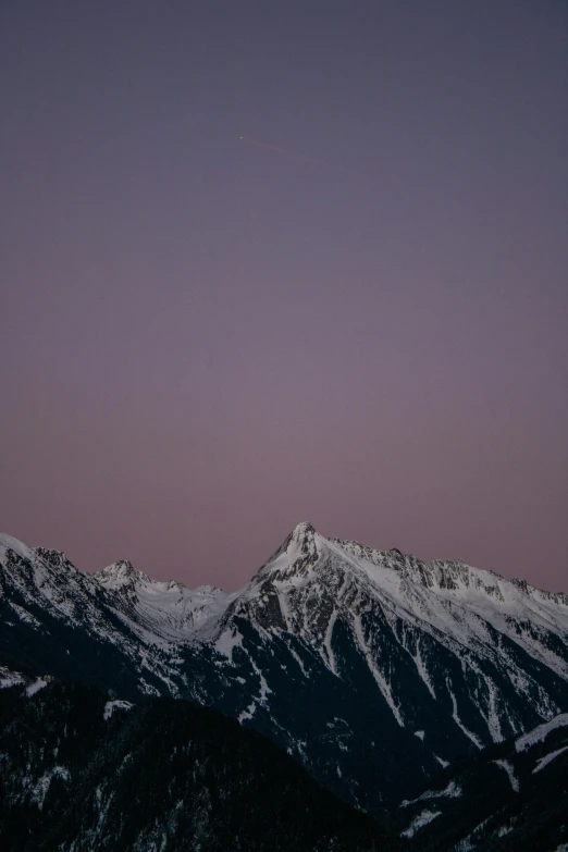 the moon setting over the mountains in the sky