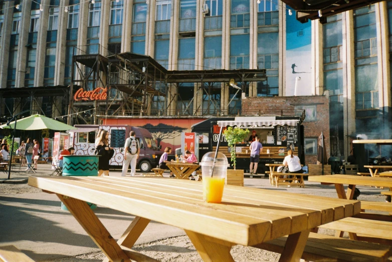 wooden benches and tables are arranged outside in a city square