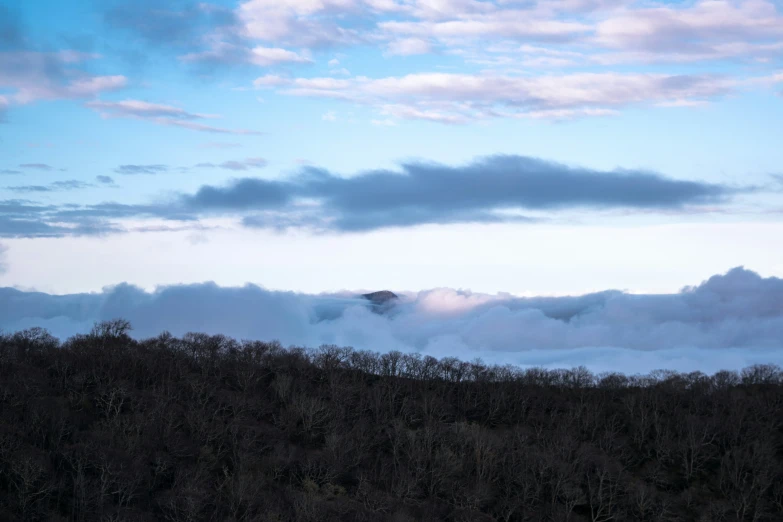 a plane flying over a hill covered in fog and clouds