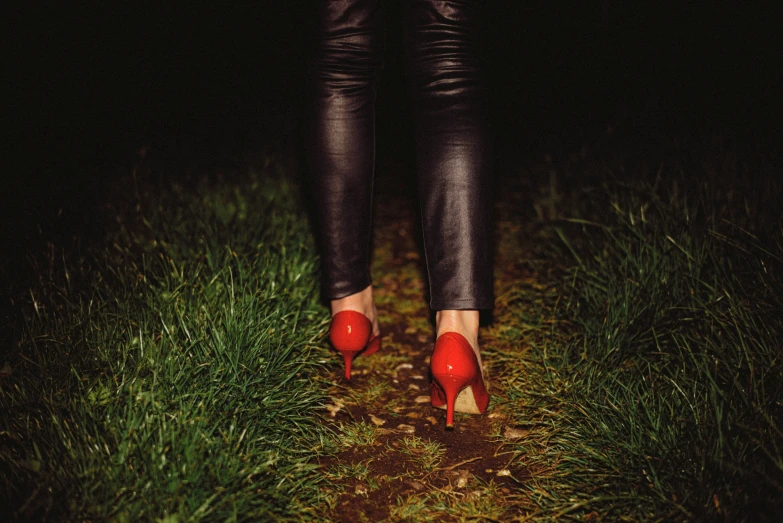 a woman with red heels is walking down the path