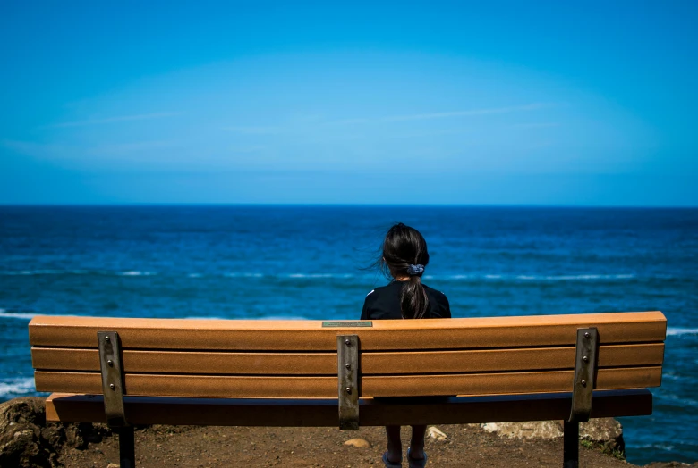 woman looking out on the ocean on a wooden bench
